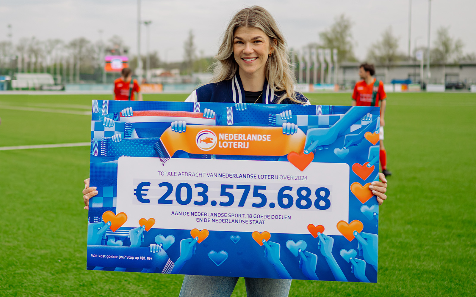 Tess Lieder met een groot bord waarop het bedrag van 203.575.688 euro staat voor de Nederlandse Loterij in 2024.