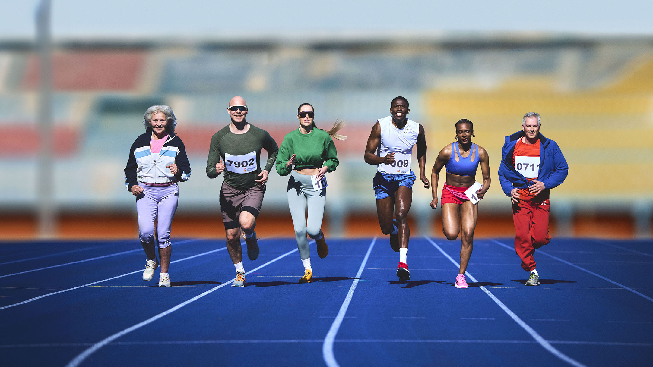 Zes atleten rennen op een blauwe atletiekbaan.